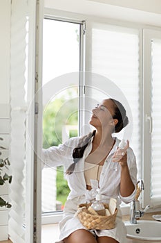 Woman cleaning window at home with rag and spray.