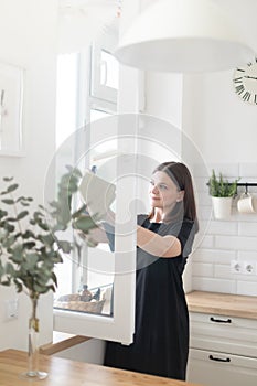 Woman cleaning window at home with rag and spray.