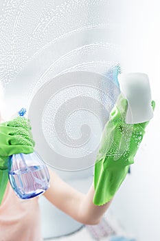 Woman cleaning window pane with detergent, cleaning concept