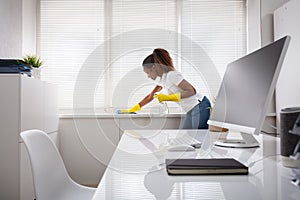 Woman Cleaning The Window Sill In Office