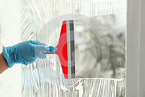 Woman cleaning window with squeegee, closeup