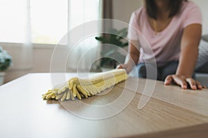 Woman cleaning and wiping the table with microfiber cloth duster in the living room. Woman doing chores at home.