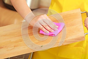 Woman cleaning wooden cutting board with rag