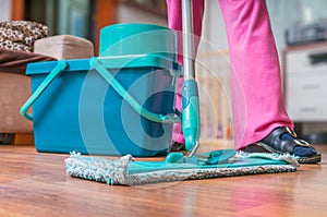 Woman is cleaning wooden floor with mop