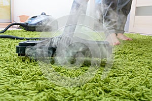 Woman cleans a carpet with a steam cleaning.