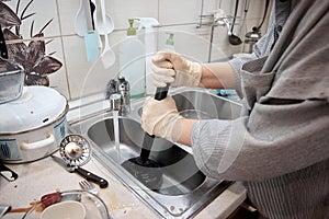 a woman cleans a clogged sink with a plunger