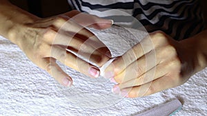 Woman cleans her fingernails with a small cotton cloth on the desk