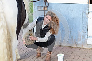 Woman cleans the horse's hooves