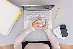 Woman clerk is sitting at office table holding note sticker with message `call mom`