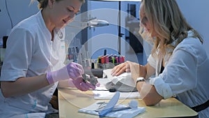 Woman client choosing color of shellac cover nails in beauty salon, side view.