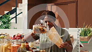 Woman client filling in paper bag with pasta sold as bulk item