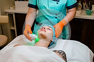 Woman client lying in beauty salon room, receives ultrasound smas non-surgical face lift by professional beautician