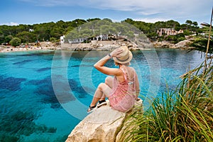 A woman on a cliff, enjoying view of Cala Gat beach in Mallorca