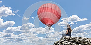 Woman on cliff with hot air balloon