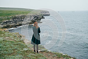 Woman on the cliff of the mountain by the sea, sadness, wind