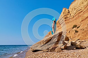 Woman on cliff sunbathing, hot summer day on coastline. Summer time, beach day, holiday trip, surfing idea, copy space