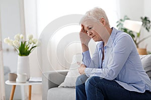 Woman Climax. Portrait Of Depressed Elderly Woman Sitting On Couch At Home