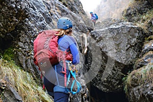 Woman climber with alpine gear, helmet, harness, backpack, looks towards the next difficult section on a mountain route in Bucegi