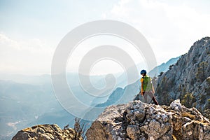 Woman climber with a backpack and a helmet in the mountains. A girl with a backpack walks along a mountain range. adventure and