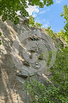 Woman climber with climbing gear equipment climbs on rock wall