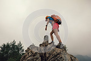 Woman climber climbing rock on the top of mountain