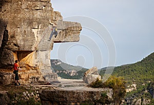 Woman climbing on cliff, male partner belaying