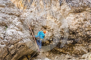 Woman climbing on metal ladder in via ferrata