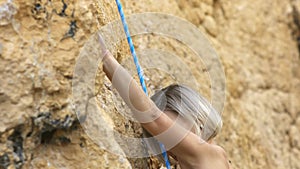 A woman is climbing a rock wall with a blue rope