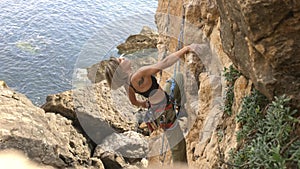 A woman is climbing a rock wall with a rope