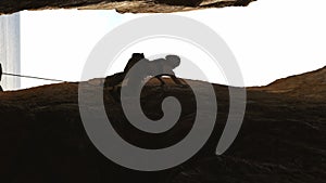 A woman is climbing a rock wall with a rope