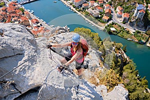 Woman climbs via ferrata Fortica above Cetina river and Omis city, Croatia. Climber, vertical, adventure, active, summer, tourism