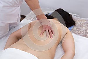 A woman in a clinic receiving a massage. Back view