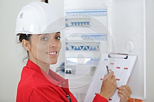 woman with clipboard inspecting electrical box