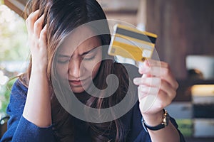 Woman close her eyes while holding credit card with feeling stressed and broke