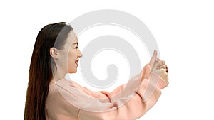 A woman, close-up, on a white background, shows her thumbs up