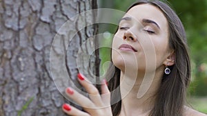 Woman with closed eyes feels tree and oneness with nature, love of life, joy