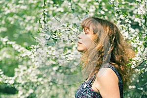 Woman with closed eyes smelling cherry blossoms