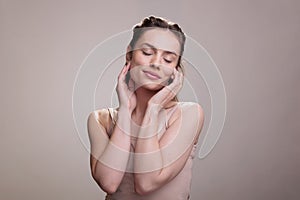 Woman with closed eyes touching face, enjoying smooth skin