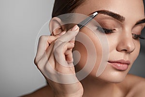 Woman With Closed Eyes And Tweezers For Eyebrows. Beauty Tools