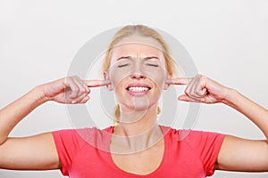 Woman closing ears with fingers, big noise.
