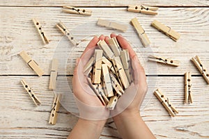 Woman with clothes pins at wooden table, top view