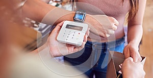 Woman In Clothing Store Making Contactless Payment With Smart Watch At Sales Desk