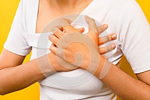 woman clutching her chest, chest pain, acute pain, heart attack, heart disease symptoms. concept of health and heart disease