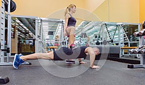 Woman coach training a man with hard push ups