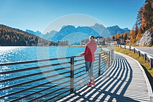 Woman on the coast of Misurina lake at sunrise in autumn