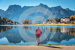 Woman on the coast of Misurina lake at sunrise in autumn