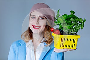 Woman in coat and beret with basket of herbs