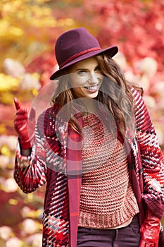 Woman in coat with hat and scarf in autumn park