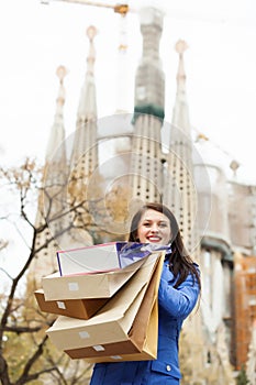 Woman in coat with purchases against Sagrada familia
