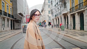 Woman in coat with smartphone in hand crossing street in city